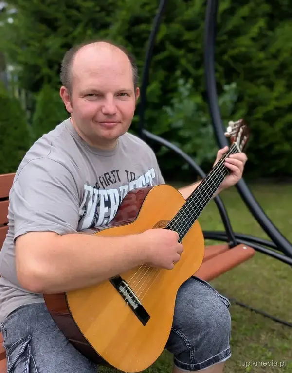 Uczestnik gra na gitarze w ogrodzie