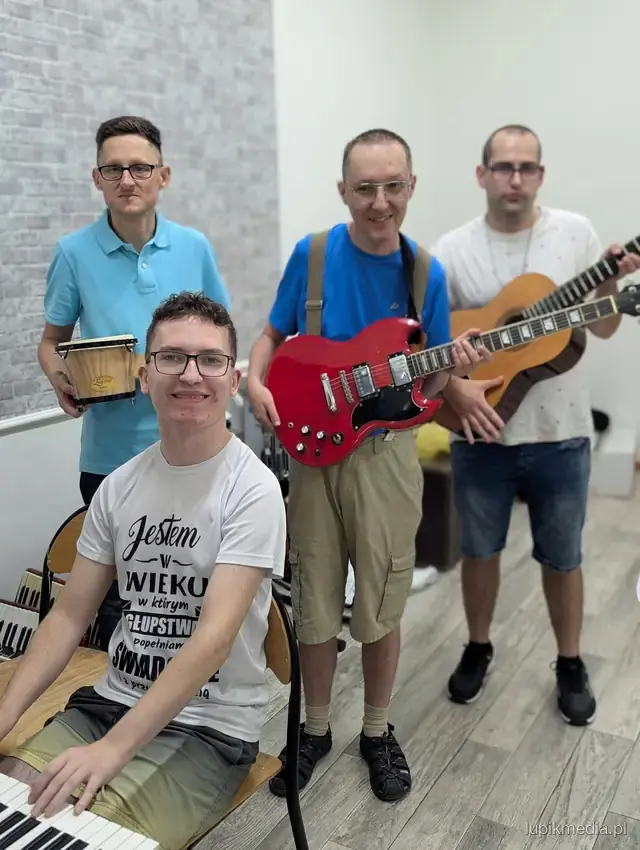Uczestnicy z gitarami i instrumentami w pracowni muzycznej